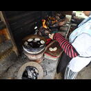 Nach dem Garen wird die obere, von Kokosnussschalen beheizte Schale abgenommen und das Gebäck kann entnommen werden